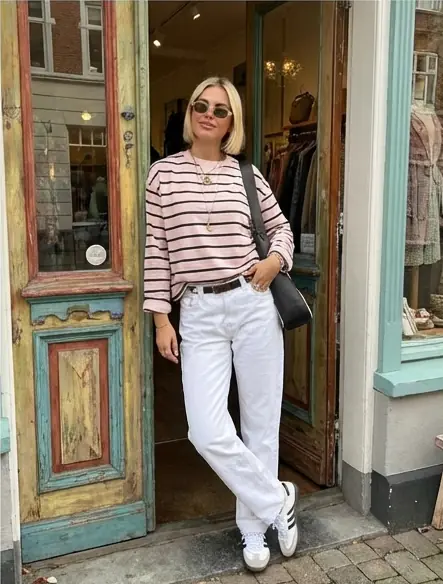 User in a striped shirt and white jeans outside a vintage shop, styled with seasonal colors from AI color analysis.