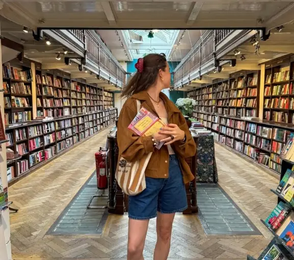 User in a bookstore wearing bright yellow shoes and earthy tones, shown as an AI color analysis result for personalized styling.
