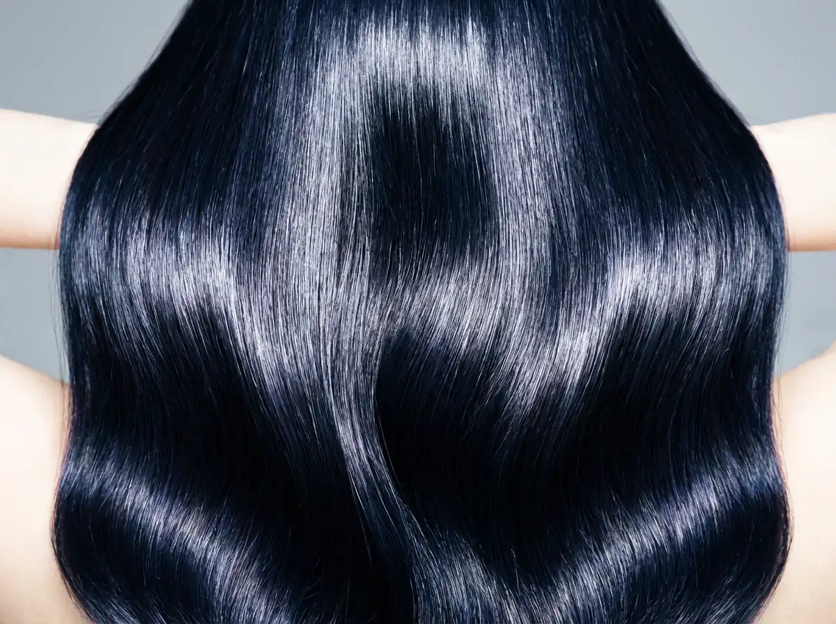 Glossy blue-black wavy hair, a recommended deep winter hair color that preserves natural depth and avoids warm blonde tones.