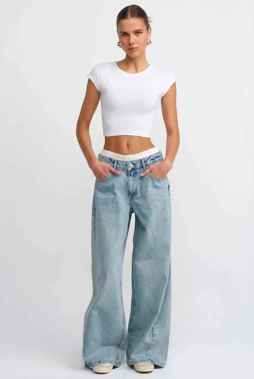 Caucasian female model in a white crop top and light blue jeans, for try-on with the AI outfit generator.