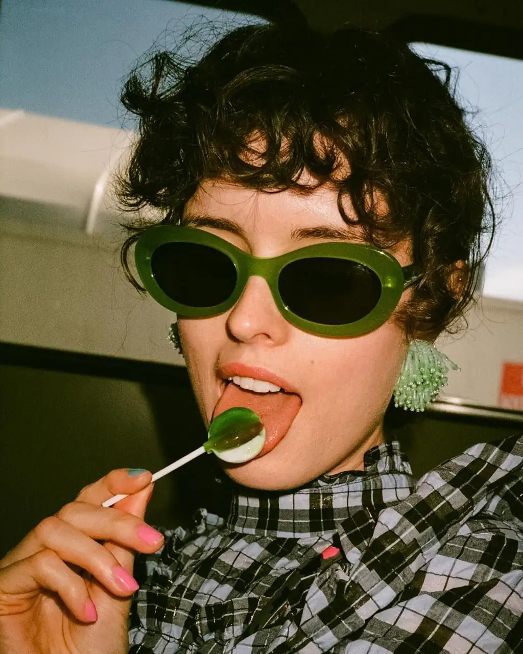 Playful woman testing bold green oval frames using virtual glasses try on tools.